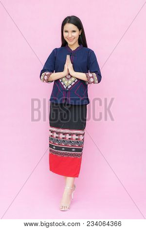 Portrait Of Asian Young Girl In Traditional Thai Dress Praying Isolated On Pink Background. Wai Sawa