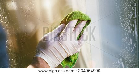 Young Man Is Using A Rag And Squeegee While Cleaning Windows.