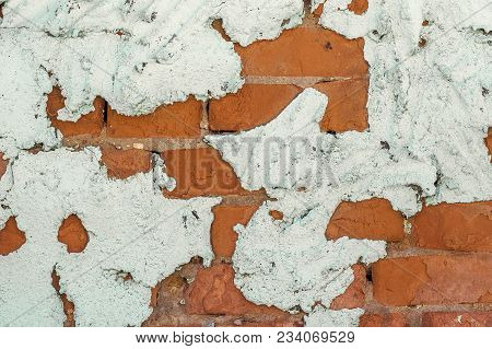 Old Brick Wall Behind A Layer Of Crumbling Painted Plaster, Background Or Texture