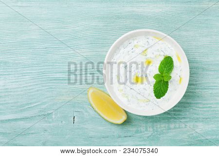 Dip Sauce Or Dressing Tzatziki From Greek Yogurt Decorated With Lemon, Mint And Olive Oil. Top View.