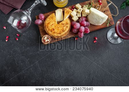Cheese Platter With Assorted Cheeses, Grapes, Nuts Over Black Background, Copy Space. Italian Cheese