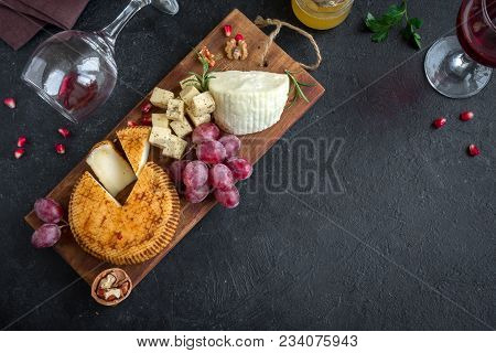 Cheese Platter With Assorted Cheeses, Grapes, Nuts Over Black Background, Copy Space. Italian Cheese
