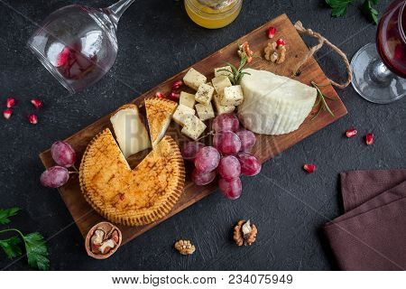 Cheese Platter With Assorted Cheeses, Grapes, Nuts Over Black Background, Copy Space. Italian Cheese