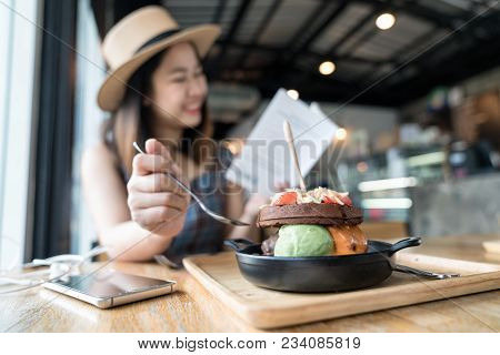Happy Asian Woman's Traveller Wearing Dress With Brown Hat Sitting And Eating Ice Cream With Chocola
