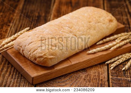 Fresh Tasty Homemade Bread On A Wooden Board. A Monotonous Still Life With Bread And Spikelets Of Ry