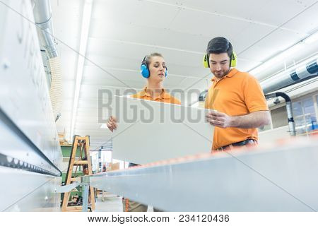 Carpenter in furniture factory inspecting piece in QA being satisfied 