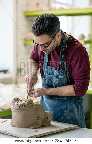 Ceramist Dressed in an Apron Sculpting Statue from Raw Clay in the Bright Ceramic Workshop.