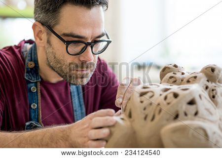 Ceramist Dressed in an Apron Sculpting Statue from Raw Clay in the Bright Ceramic Workshop.