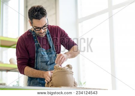 Ceramist Dressed in an Apron Sculpting Statue from Raw Clay in the Bright Ceramic Workshop.