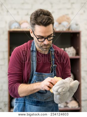 Portrait of Ceramist Dressed in an Apron Working on Clay Sculpture in the Bright Ceramic Workshop.