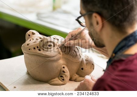 Ceramist Dressed in an Apron Sculpting Statue from Raw Clay in the Bright Ceramic Workshop.