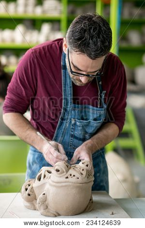 Ceramist Dressed in an Apron Sculpting Statue from Raw Clay in the Bright Ceramic Workshop.