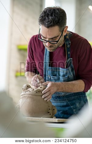 Ceramist Dressed in an Apron Sculpting Statue from Raw Clay in the Bright Ceramic Workshop.