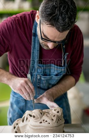 Ceramist Dressed in an Apron Sculpting Statue from Raw Clay in the Bright Ceramic Workshop.