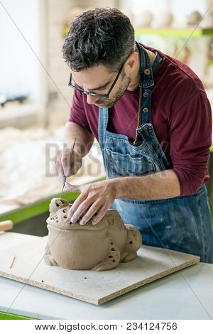 Ceramist Dressed in an Apron Sculpting Statue from Raw Clay in the Bright Ceramic Workshop.