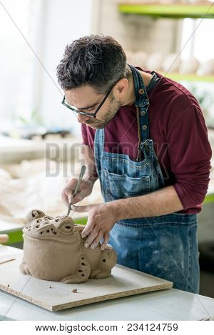 Ceramist Dressed in an Apron Sculpting Statue from Raw Clay in the Bright Ceramic Workshop.