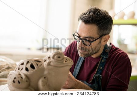 Ceramist Dressed in an Apron Sculpting Statue from Raw Clay in the Bright Ceramic Workshop.