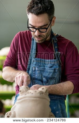 Ceramist Dressed in an Apron Sculpting Statue from Raw Clay in the Bright Ceramic Workshop.