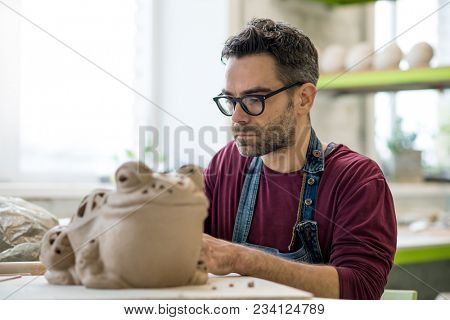 Ceramist Dressed in an Apron Sculpting Statue from Raw Clay in the Bright Ceramic Workshop.