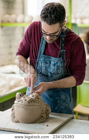 Ceramist Dressed in an Apron Sculpting Statue from Raw Clay in the Bright Ceramic Workshop.