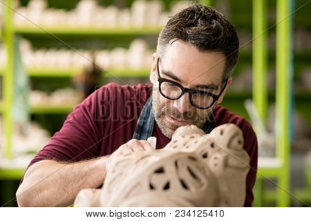 Ceramist Dressed in an Apron Sculpting Statue from Raw Clay in the Bright Ceramic Workshop.