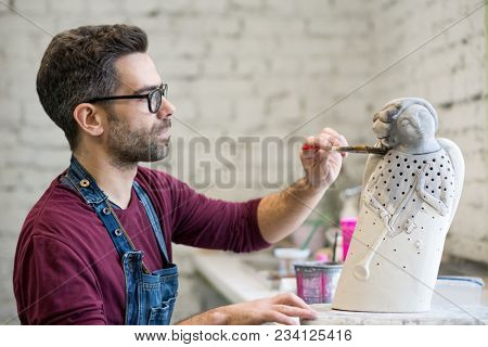 Portrait of Ceramist Dressed in an Apron Working on Clay Sculpture in the Bright Ceramic Workshop.