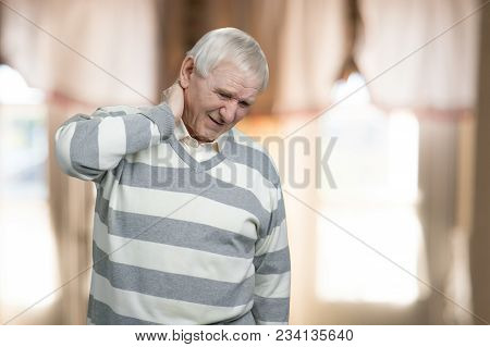 Old Man Has Neck Pain. Senior Suffers From Neckache Indoor At Home.