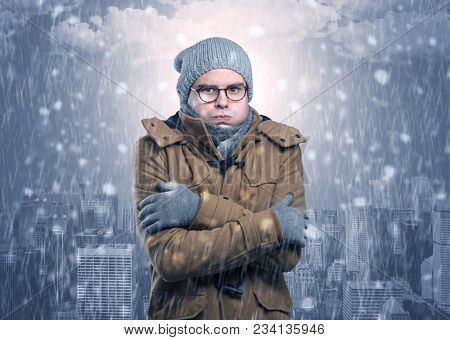 Young man freezing in warm clothing with city concept