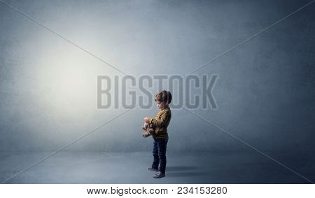 Little waggish kid staying alone in a big empty room with his plush