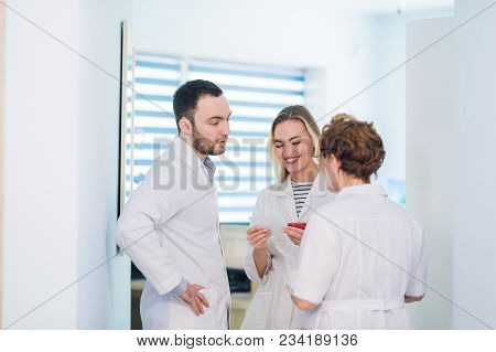 Mature Doctor Discussing With Nurses In A Hallway Hospital. Doctor Discussing Patient Case Status Wi