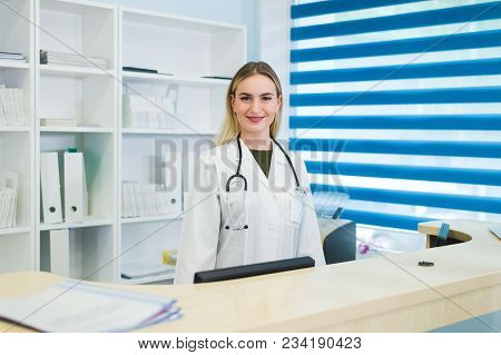 Smiling Female Doctor With Stethoscope At The Reception.
