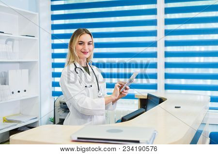Smiling Female Doctor With Stethoscope At The Reception.
