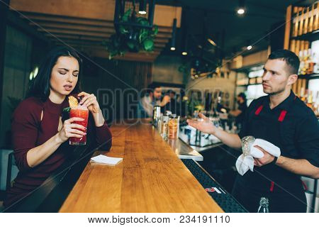 A Girl That Is Not Satisfied With The Cocktail That Barman Has Made For Her. She Looks Dissapointed.