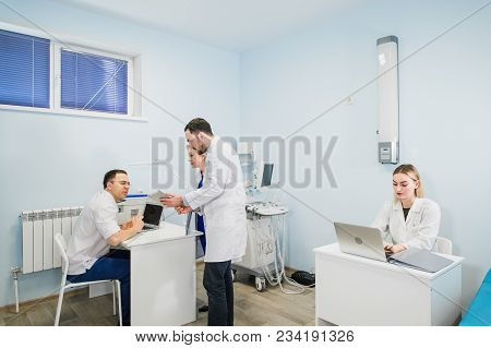 Group Of Doctors Involved In Serious Discussion With Medical Records.