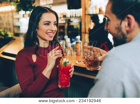 Beautiful Girl Sitting In The Club With Ac Guy. She Holds A Glass Of Cocktail In Her Hands. She Is L
