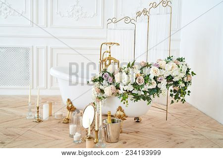 Beautiful Luxury Vintage Empty Bathtub With Lush Floral Decorations And Candles, Mirror On The Floor