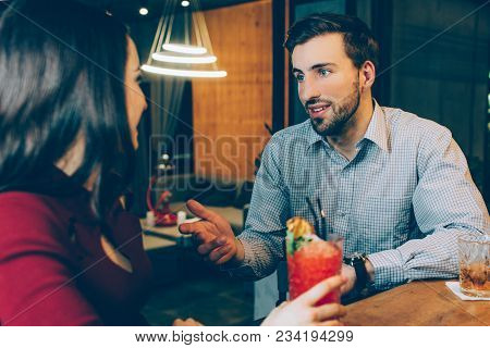 Lovely Picture Of Man Sitting In Bar And Talking To Woman. He Looks Good And Well-built. She Is Hold
