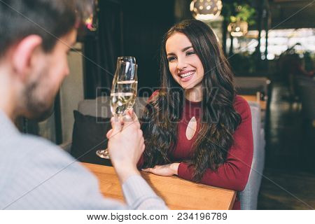 Lovely Picture Of Beautiful Couple Sitting At The Table And Drinking Champaigne. They Are Celebratin