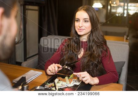 Lovely Girl Is Sitting In Front Of Her Boyfriend And Looking At Him. She Is Ready To Eat Salads That