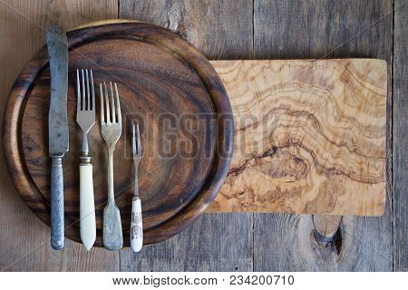 Stainless Steel Cutlery On A Wooden Chopping Board.