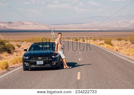 Young Man Standing By The Ford Mustang Gt Convertible At The Side Of A Long Infinite Road In The Mid