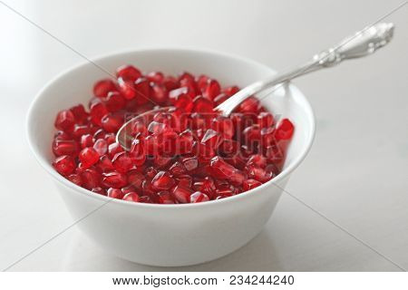 Grains Of Red Ripe Pomegranate Lie In A White Bowl With A Spoon. Big Ripe Red Granets Or Garnets. Fr
