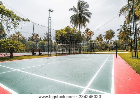 Side Wide-angle View Of The Badminton Court On A Summer Day: Red And Green Field With Marking On The