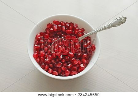 Grains Of Red Ripe Pomegranate Lie In A White Bowl With A Spoon. Big Ripe Red Granets Or Garnets. Fr