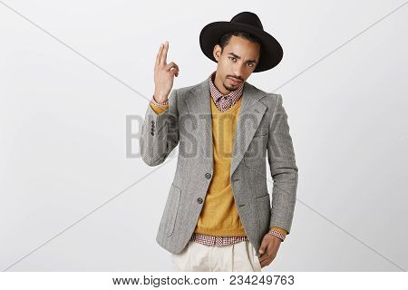 What Are You Looking At. Confident Good-looking Dark-skinned Man In Black Hat And Gray Jacket, Showi
