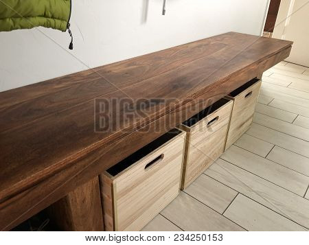 Wood Bench With Wooden Shoe Boxes Underneath In The Laundry Room Of A House Remodel.