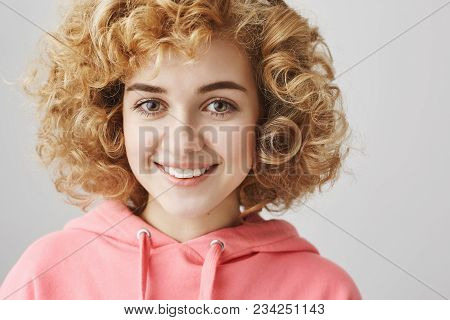 Close-up Portrait Of Cute Feminine Caucasian Girl With Frizzle Hairstyle Smiling Broadly While Stand