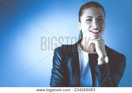 portrait of beautiful young brunette woman in stylish black jacket on gray.