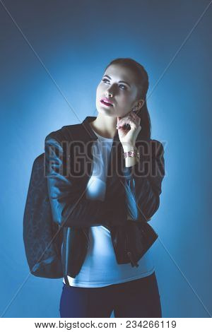 portrait of beautiful young brunette woman in stylish black jacket on gray.
