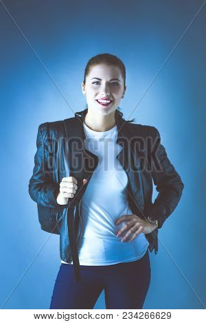 portrait of beautiful young brunette woman in stylish black jacket on gray.